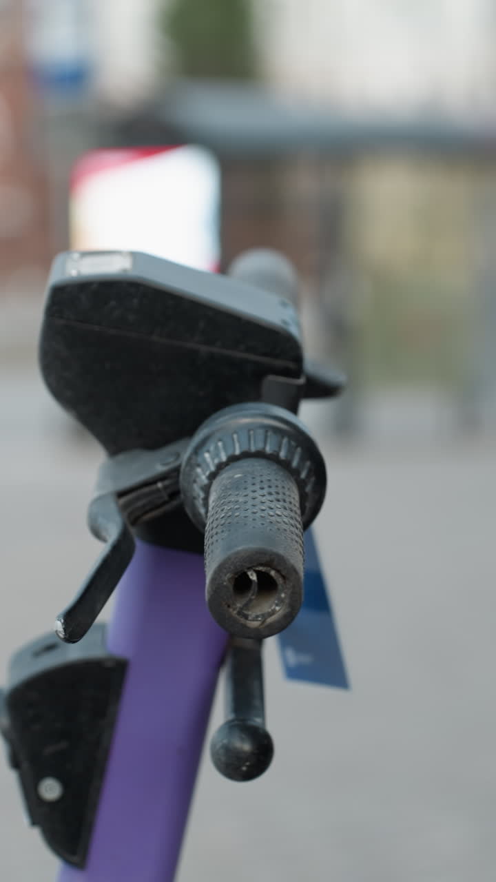 vista cercana de scooters eléctricos púrpuras estacionados en un área urbana ocupada, el fondo incluye detalles borrosos de un paisaje urbano con coches en movimiento y personas