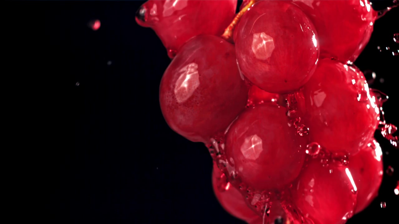 Uva rossa fresca con schizzi d'acqua al rallentatore