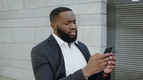 African-businessman-getting-bad-news-on-phone.-Business-man-walking-on-street