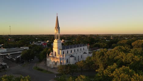 aerial view orbiting around virgen niña catholic church in villa elisa town at golden hour