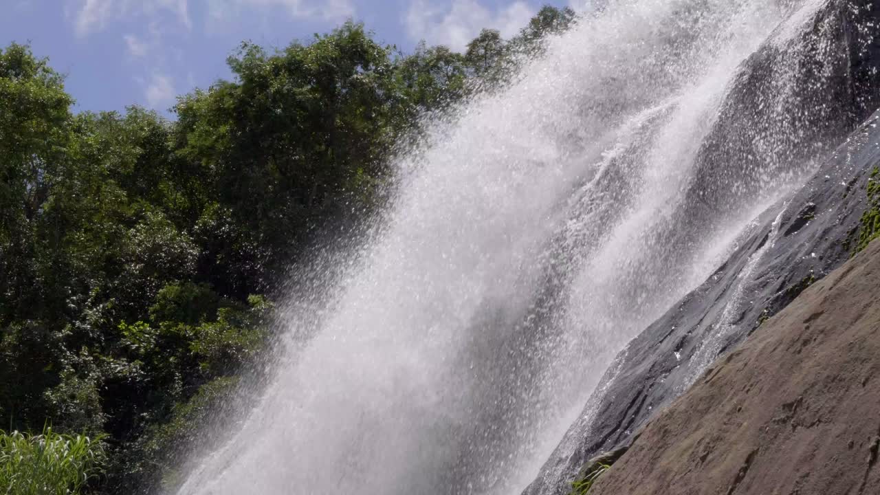 cerca de las aguas que fluyen rápidamente desde la cascada sobre el terreno de la roca de boulder