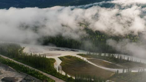 drone descendente disparado a través de las nubes colgando en un valle sobre el río kicking horse a las afueras del parque nacional yoho