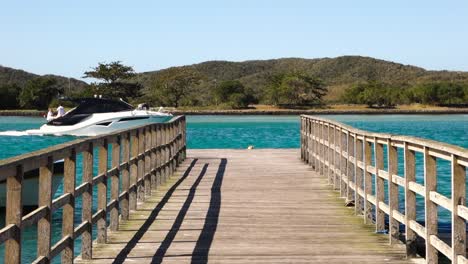 perspective view of a wooden pier on tropical sea bay, yacht and boats sailing beside it