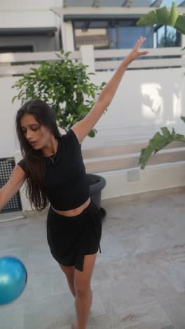 teen girl practicing gymnastics on patio with ball