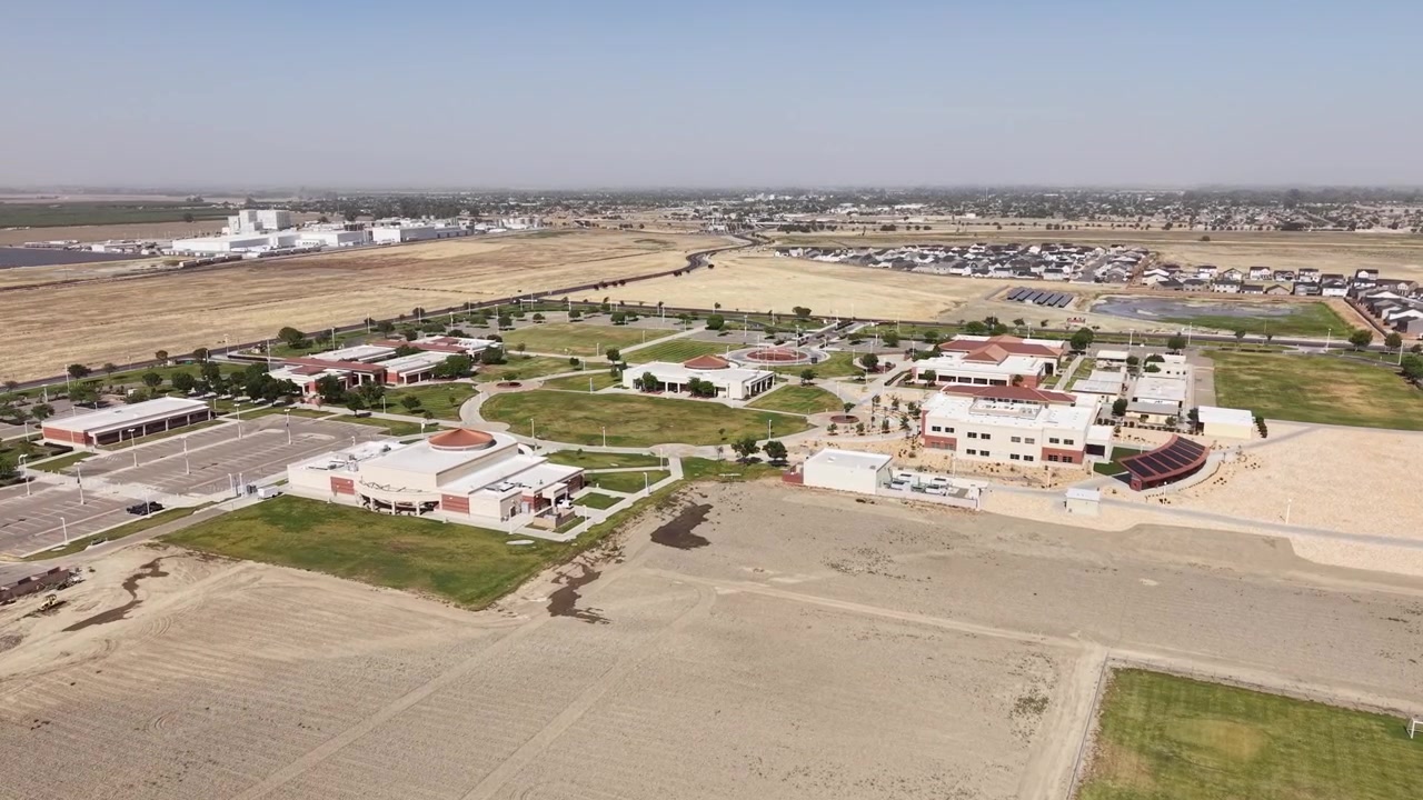 Zoom aereo sul campus del West Hills College Lemoore nella Central Valley della California, che mostra gli edifici, il parcheggio e il paesaggio arido circostante