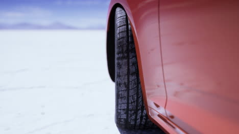 close up of tire on vehicle driving across vast salt flats at sunset