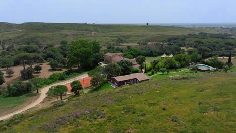 aerial shot of a villa with a private swimming pool and clay tennis court