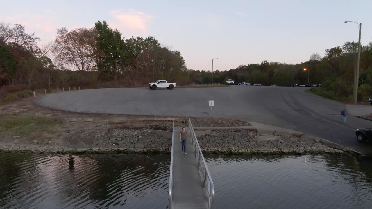 호수를 향해 도크를 걸어가는 소녀의 돌리 거꾸로 샷