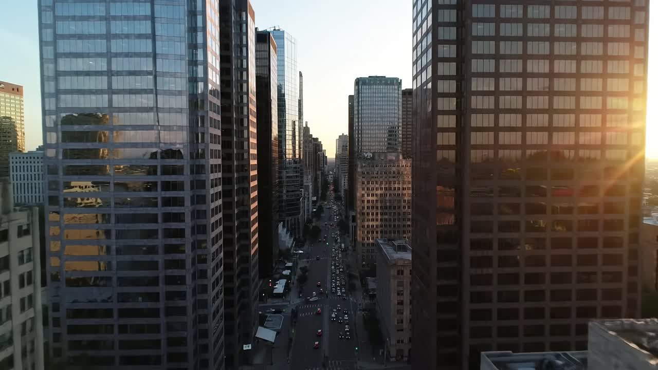 Cautivadora vista aérea del paisaje urbano al anochecer, mostrando imponentes rascacielos y calles concurridas bañadas por la luz dorada del atardecer.