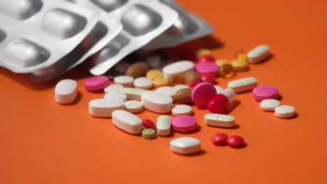 assorted pills and blister packs on orange surface