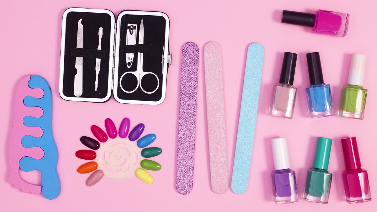 las herramientas de manicura y las botellas de esmalte de uñas se mueven sobre un fondo rosa brillante. diseño creativo de herramientas de manucura en movimiento. stop motion flay lay