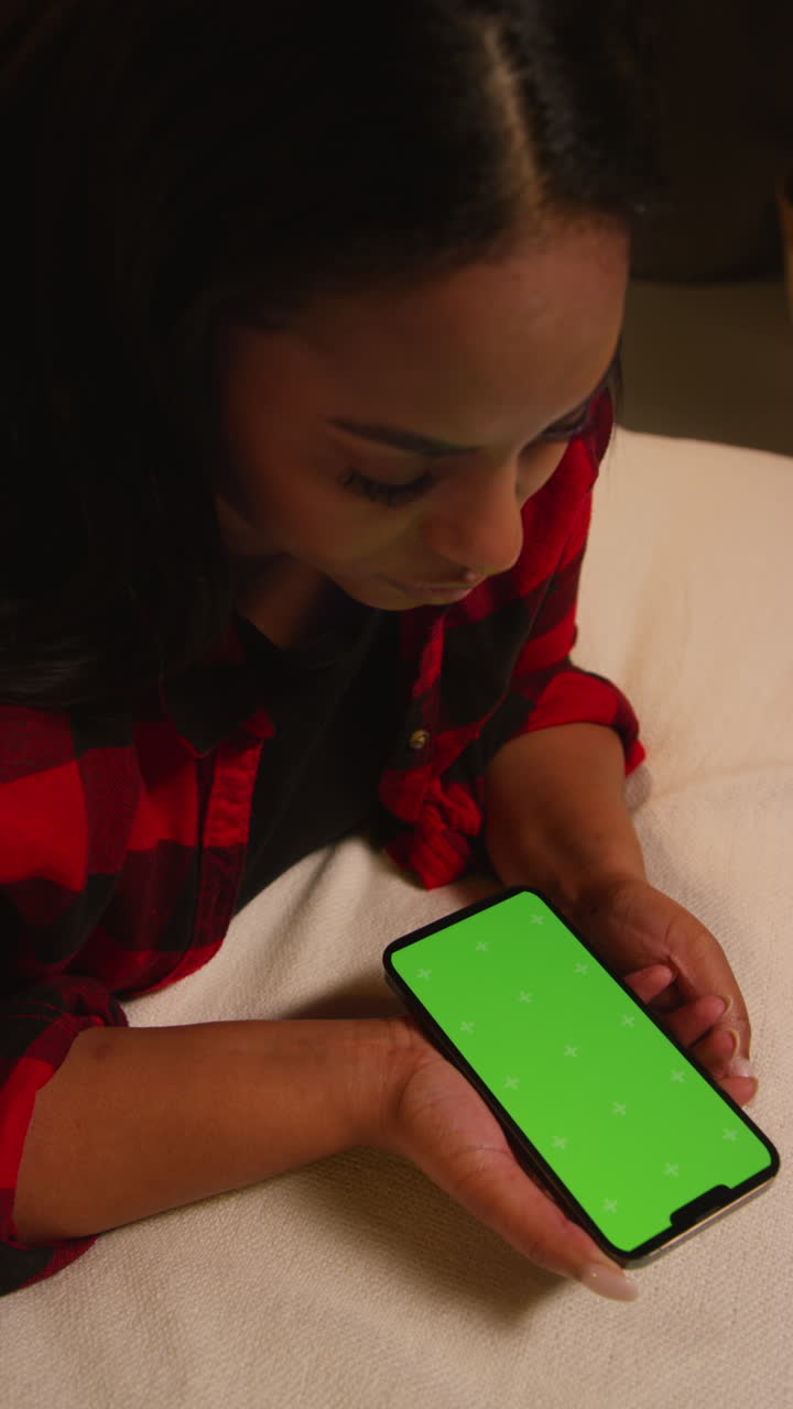 Donna che usa uno smartphone sdraiata su un letto