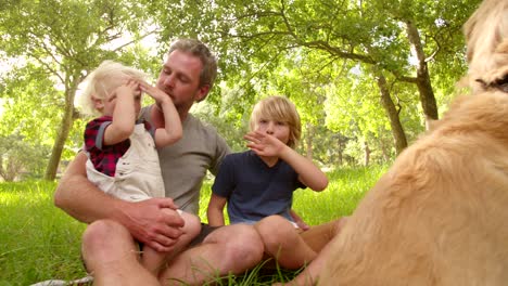 dad plays with his cute sons and their dog outside