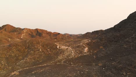 aerial shot of the mountain hills of by a highway in showka, fujairah during sunset with orange sky