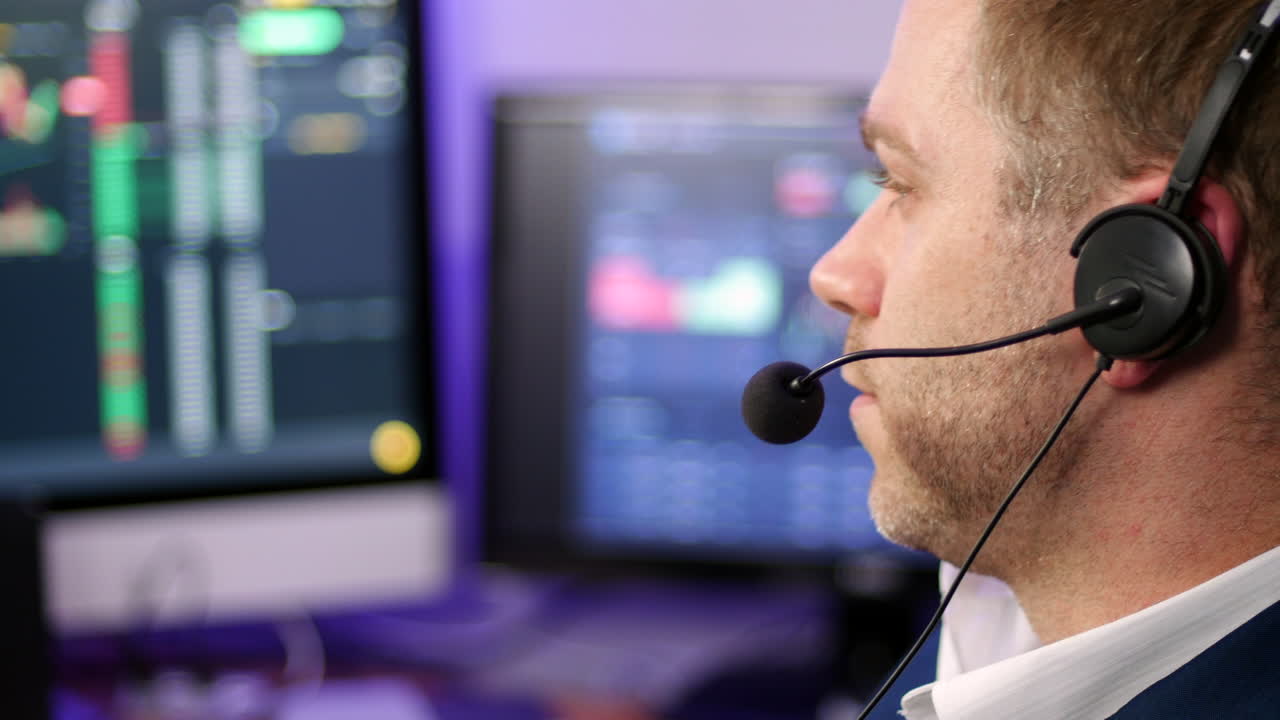 Chatting man in techical support wearing a headset in a trading broker office