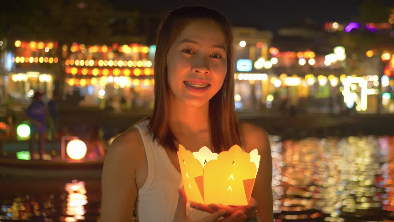 la linterna tradicional ilumina la cara del turista asiático por la noche - hoi an riverfront