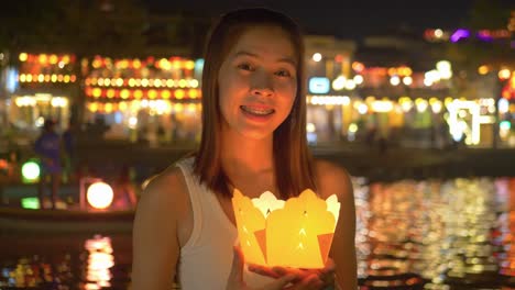 traditional lantern lights up face of asian tourist at night - hoi an riverfront