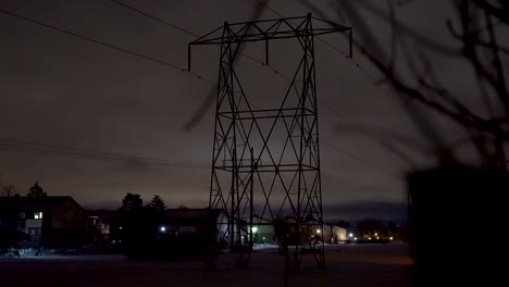 toma reveladora de una torre hidroeléctrica de noche en una zona suburbana nevada.