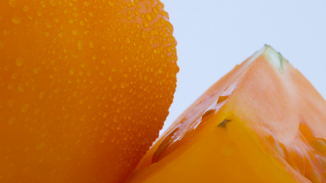 물방울을 가진 작은 부분을 가진 전체 큰 노란 토마토의 매크로 촬영, 백색 배경에 고립 된 회전 테이블에서 천천히 회전.