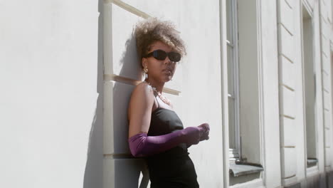 young elegant african woman leaning on the wall of a building