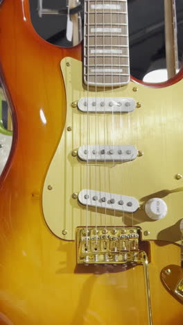 close-up of colorful electronic guitars hanging on the wall of a shop. a collection of bass guitars. vertical video.