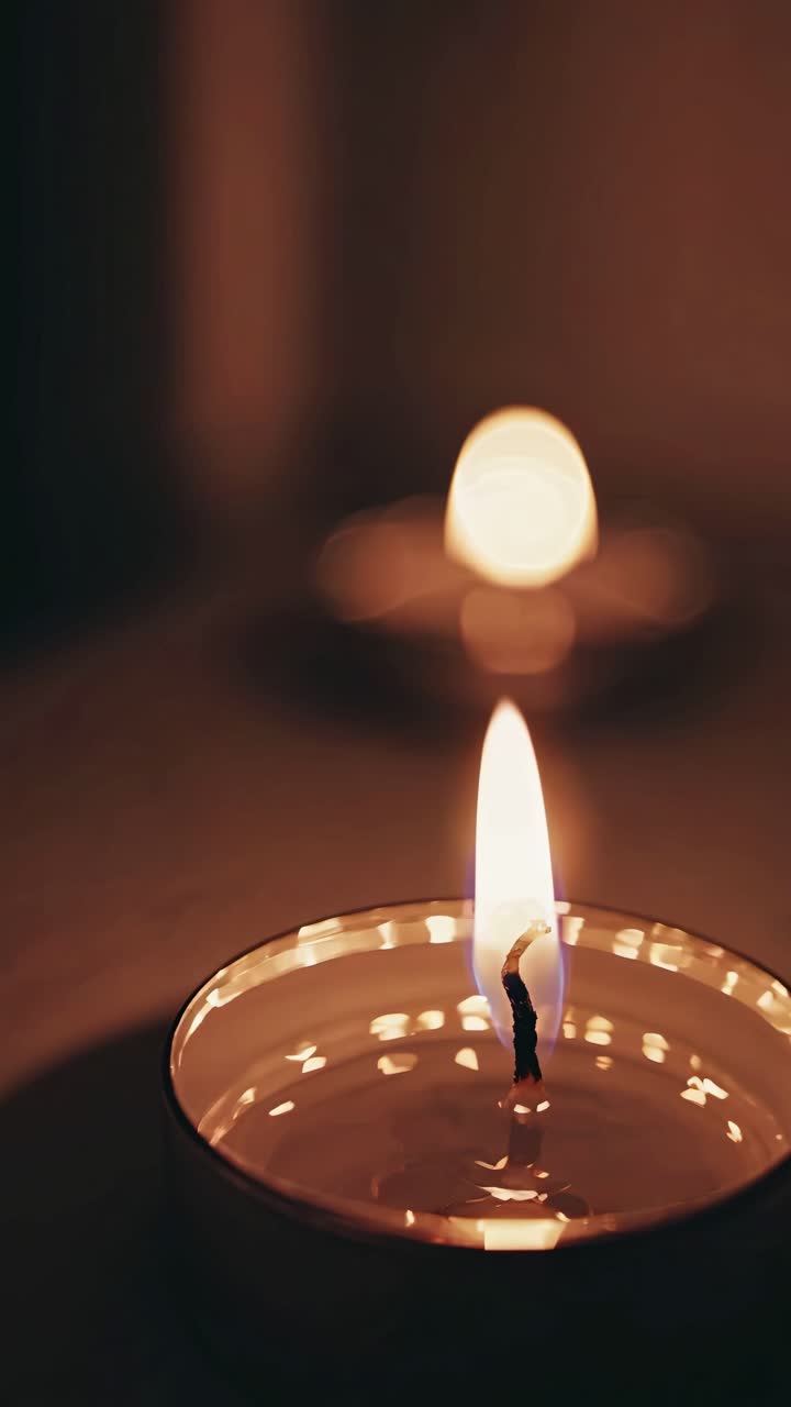 Video ravvicinato dai toni caldi di una fiamma di candela che tremola dolcemente, ripreso da una bassa angolazione