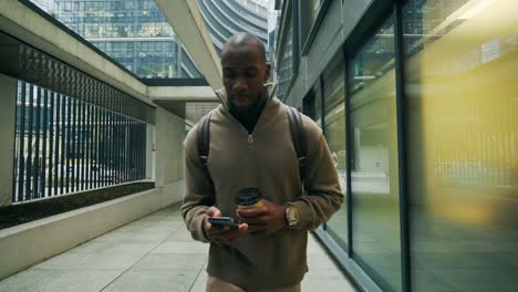 businessman walking in a city with a coffee and smartphone