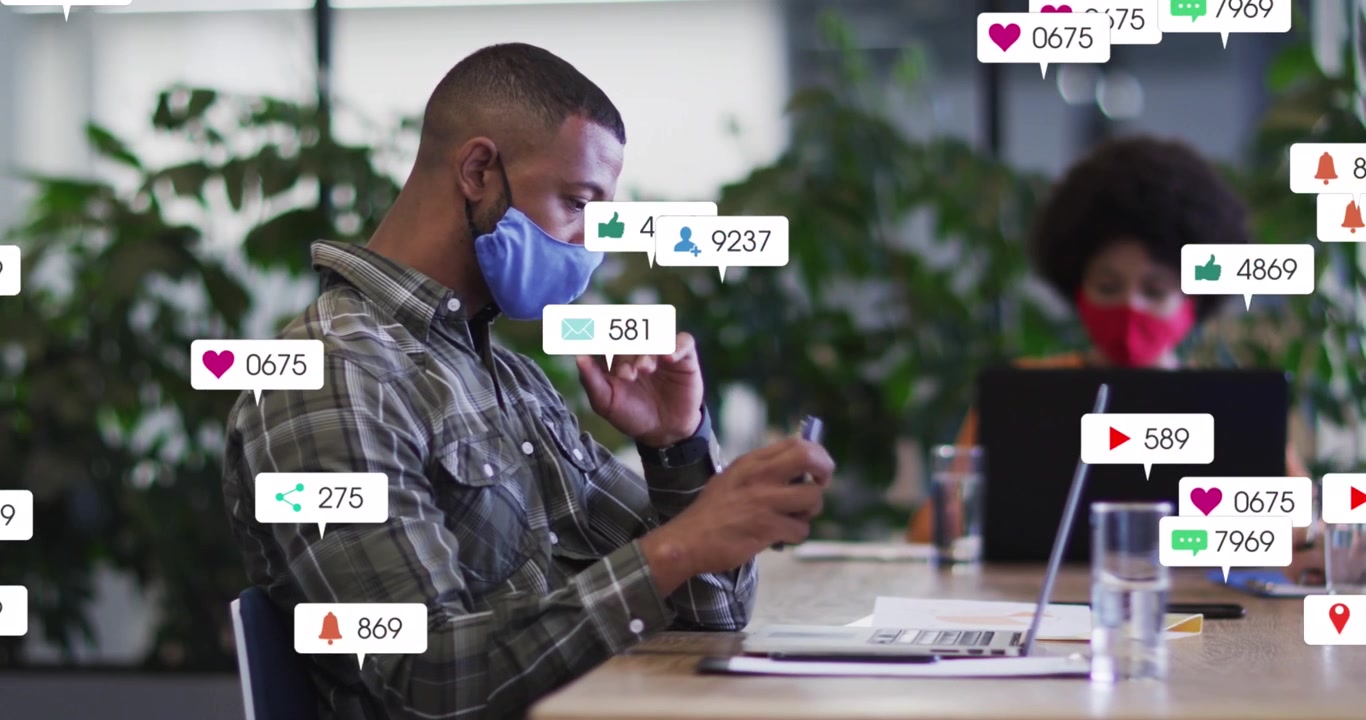 Animation of social media icons over businessman wearing face mask