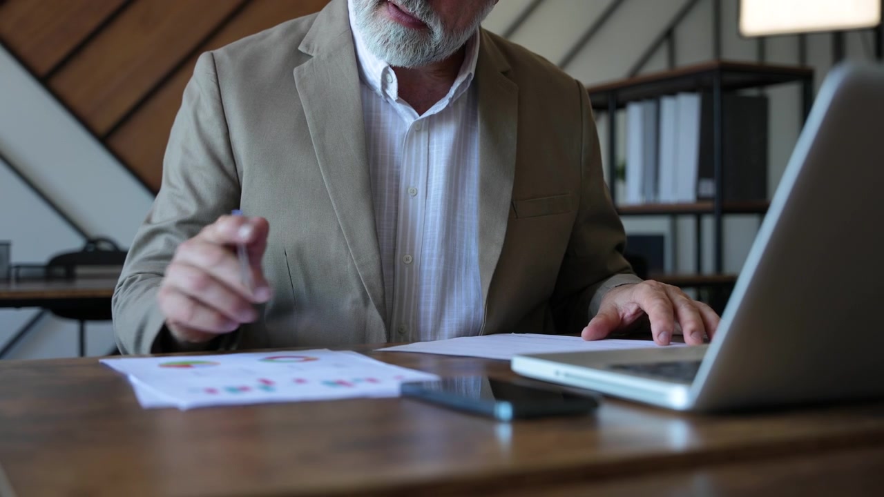 Dirigente Senior Che Analizza Grafici Finanziari Alla Scrivania Dell'Ufficio