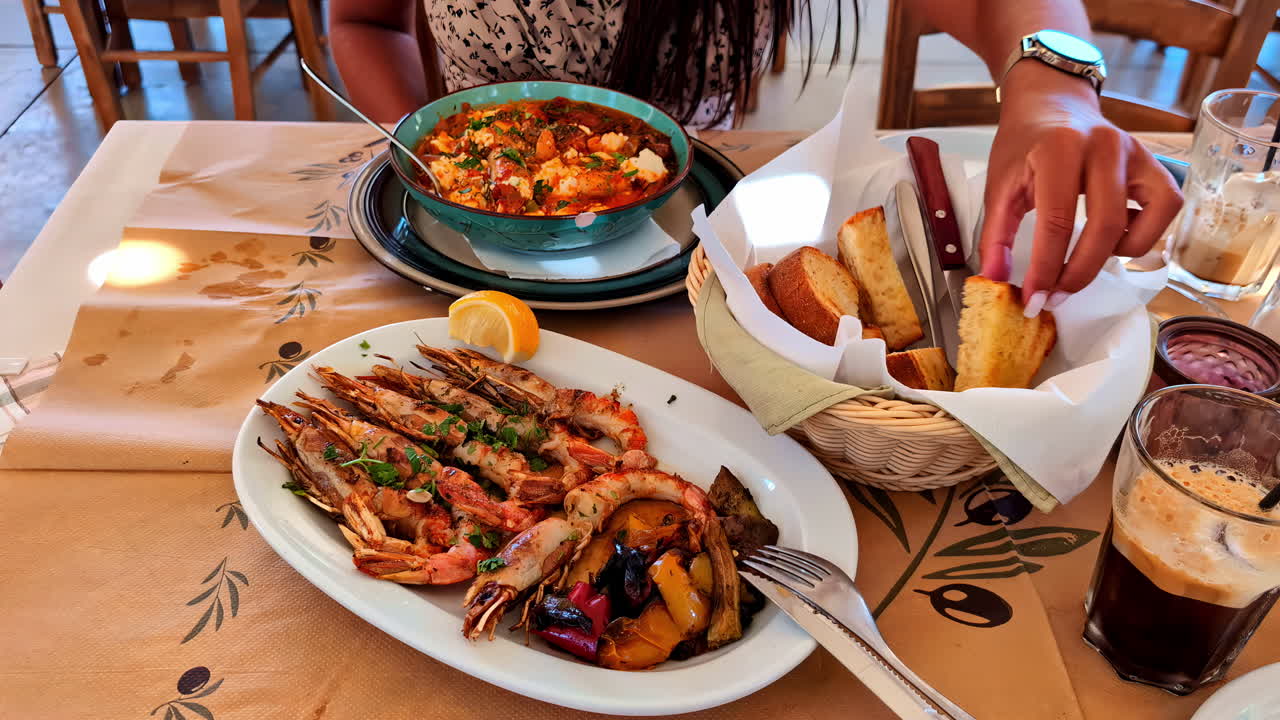 Woman eating bread accompanied by a plate of prawns