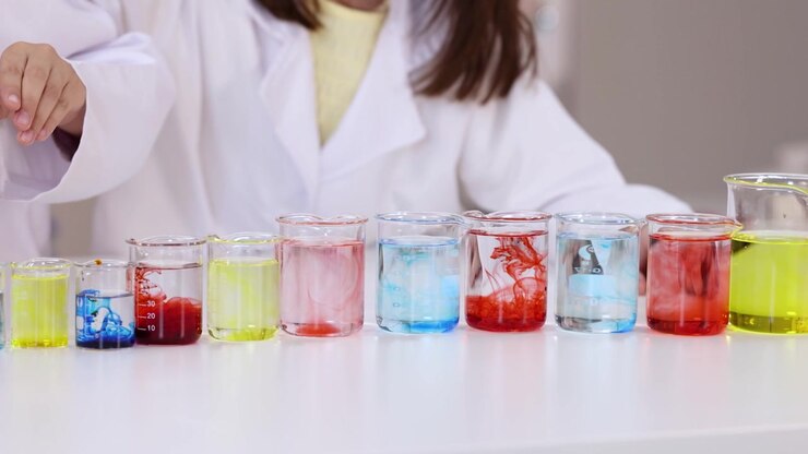 Gli studenti usano pipette per far cadere il colorante nei becher durante una vivace lezione STEM in classe.