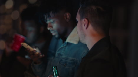 group of friends relaxing on rooftop at night using smartphone technology texting sharing social media lifestyle browsing online enjoying weekend party