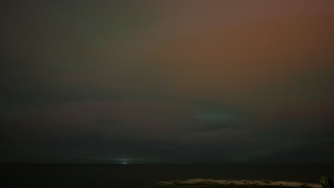 timelapse of aurora borealis lighting up starry sky and low clouds in iceland