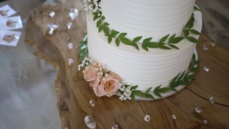 close up of a white wedding cake adorned with pink roses, greenery, and sparkling crystal decor