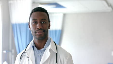 portrait of african american male doctor smiling in hospital ward, copy space, slow motion