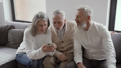 grupo de felices amigos mayores sentados en el sofá y divirtiéndose juntos