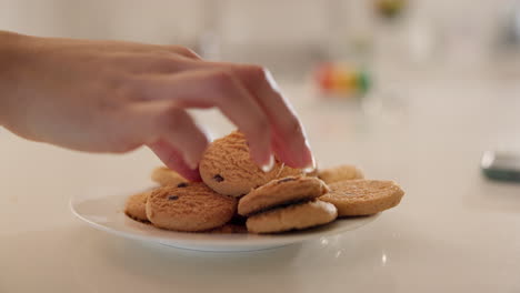 Hands,-cookies-and-plate-on-table-in-home-kitchen