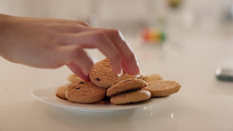 hands, cookies and plate on table in home kitchen