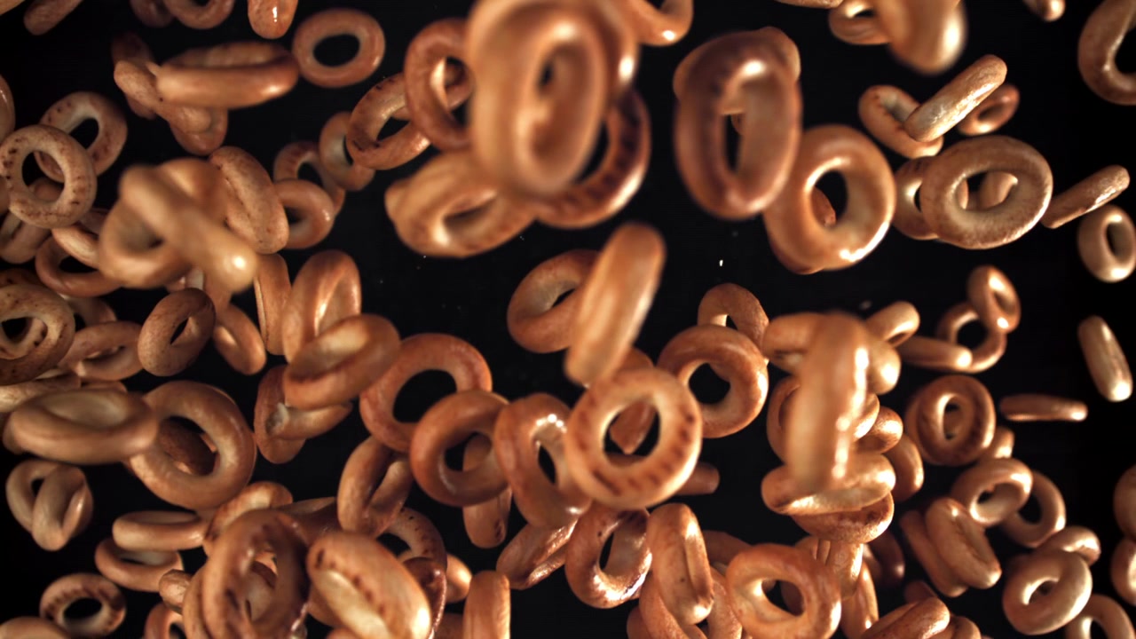 Piccoli bagel che cadono al rallentatore su sfondo nero.