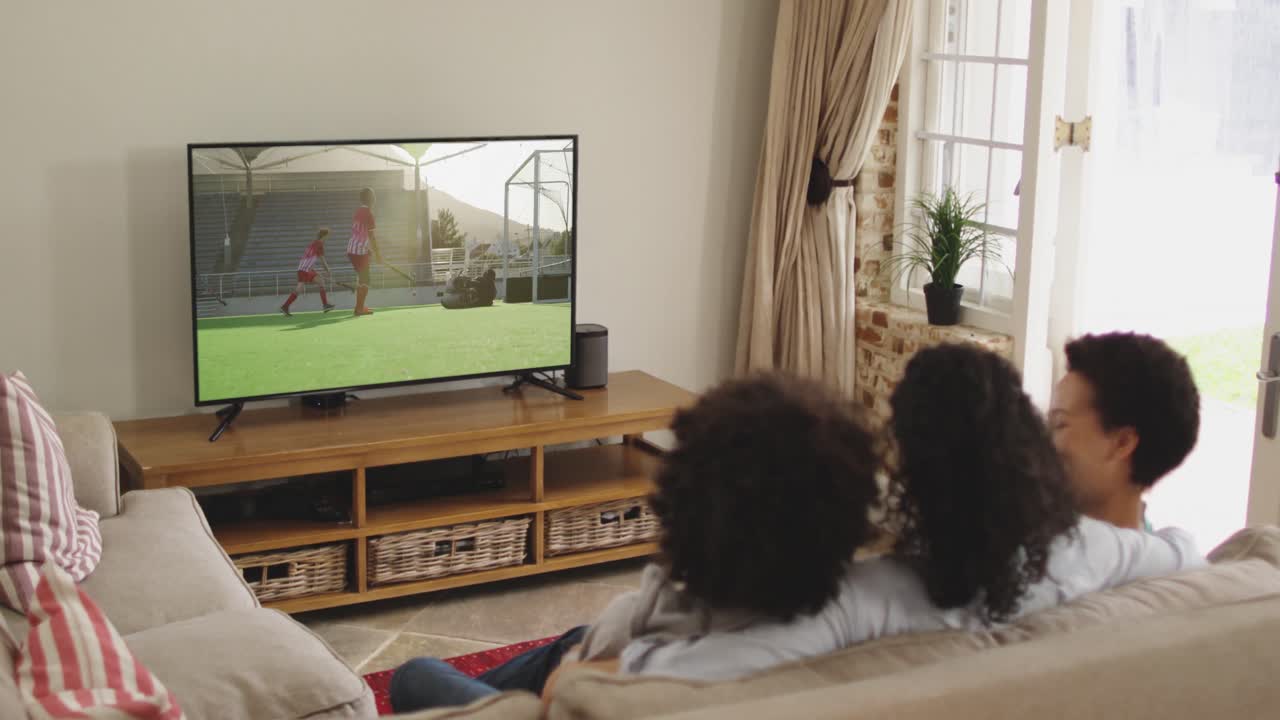 Famiglia felice seduta a casa insieme che guarda una partita di hockey in TV