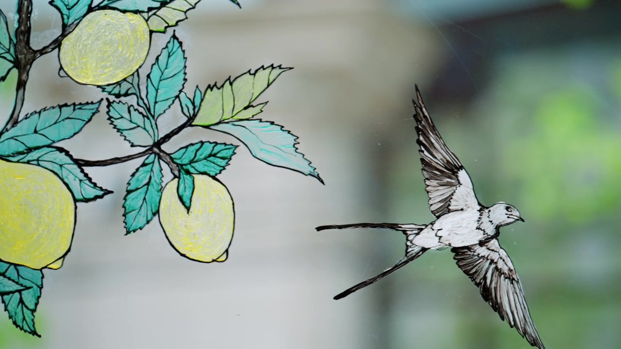 Nærbillede af et dekorativt glaspanel med en håndtegnet illustration af gule citroner på bladfyldte grene og en flyvende fugl, der ligner en svale.