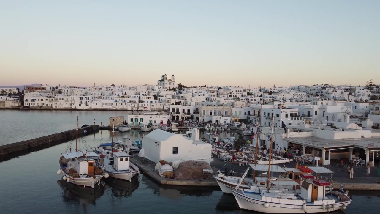 Ripresa drone del vecchio porto di Naousa, case cicladiche imbiancate a calce, vivace porto veneziano al tramonto, Paros, Mar Egeo