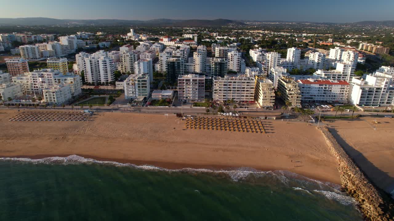 panorámica lateral vista aérea de la playa, el paseo marítimo y los edificios en quarteira, algarve, portugal