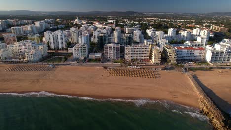 side panning aerial view of beach, boardwalk and buildings in quarteira, algarve, portugal