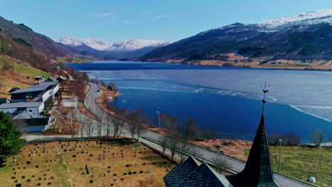 panoramic view of a half frozen fjord and snow capped mountains in the background