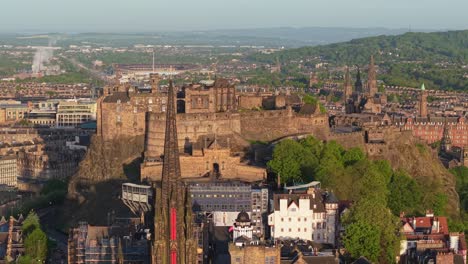 smooth drone orbit capturing edinburgh’s vibrant cityscape, featuring the hub in the foreground and the majestic edinburgh castle in the background at sunset