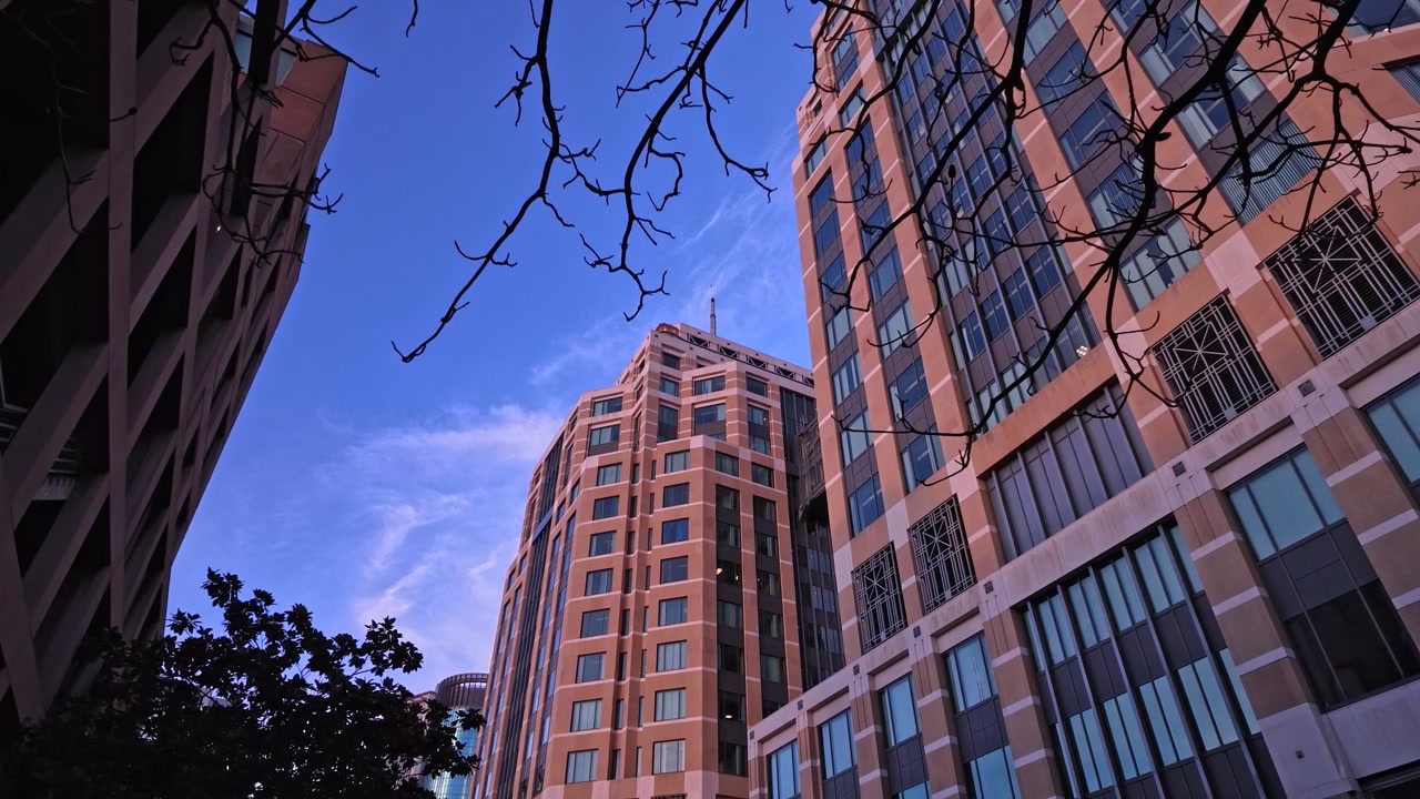 Prospettiva dal basso dell'architettura moderna del Ronald V. Dellums Federal Building a Oakland, California, con un cielo azzurro limpido e nuvole leggere sullo sfondo.