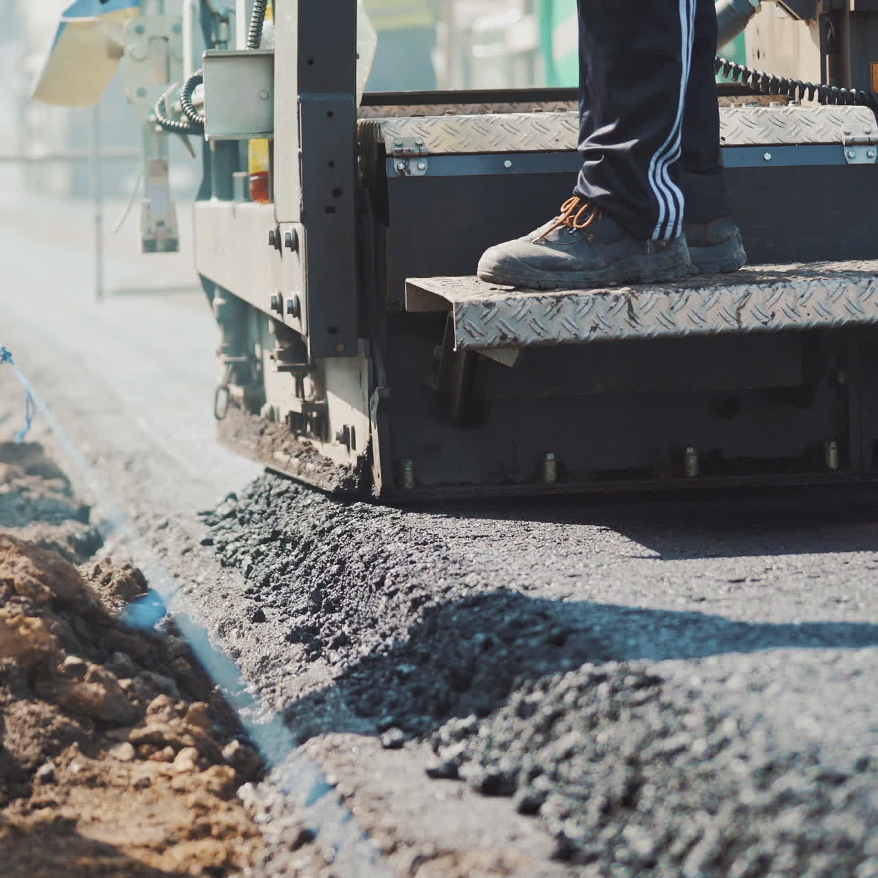 Asphalt paver machine laying hot asphalt to the road and workers control. Spillage of asphalt on the highway. Fresh asphalt resurfacing the street. New service of technology asphalting.