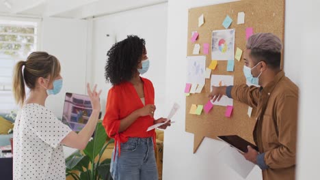 office colleagues wearing face mask discussing over memo notes at office