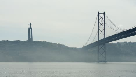 beautiful lisbon suspended bridge over quiet river and cristo rei statue, portugal